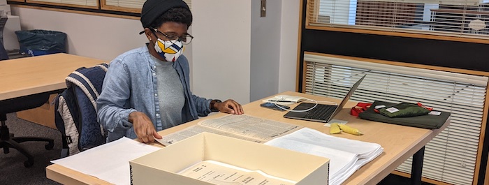 Dr. Kianna Middleton sits at a table in the Morgan Library Reading Room. She is reviewing print materials from the CSU Libraries' Friedman Feminist Press Collection.