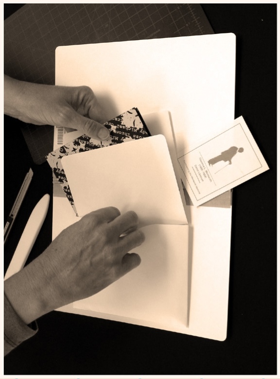 A pair of hands putting folded paper into an envelope