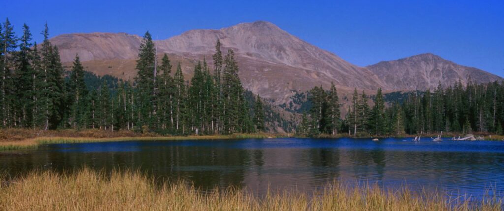 A beautiful mountain landscape with a body of water in the foreground.