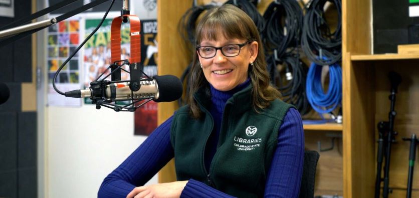 Patty Rettig seated before a microphone in a podcast studio.