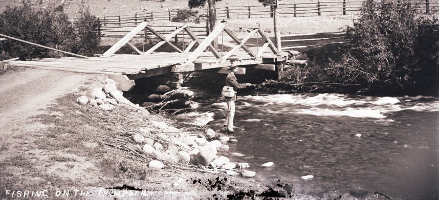 Vintage black and white photo of a person fly-fishing in the Big Thompson River, with the handwritten caption 'Fishing on the Thompson'.