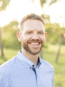 Headshot of Teddy Ogilvie, a white man with short hair and glasses